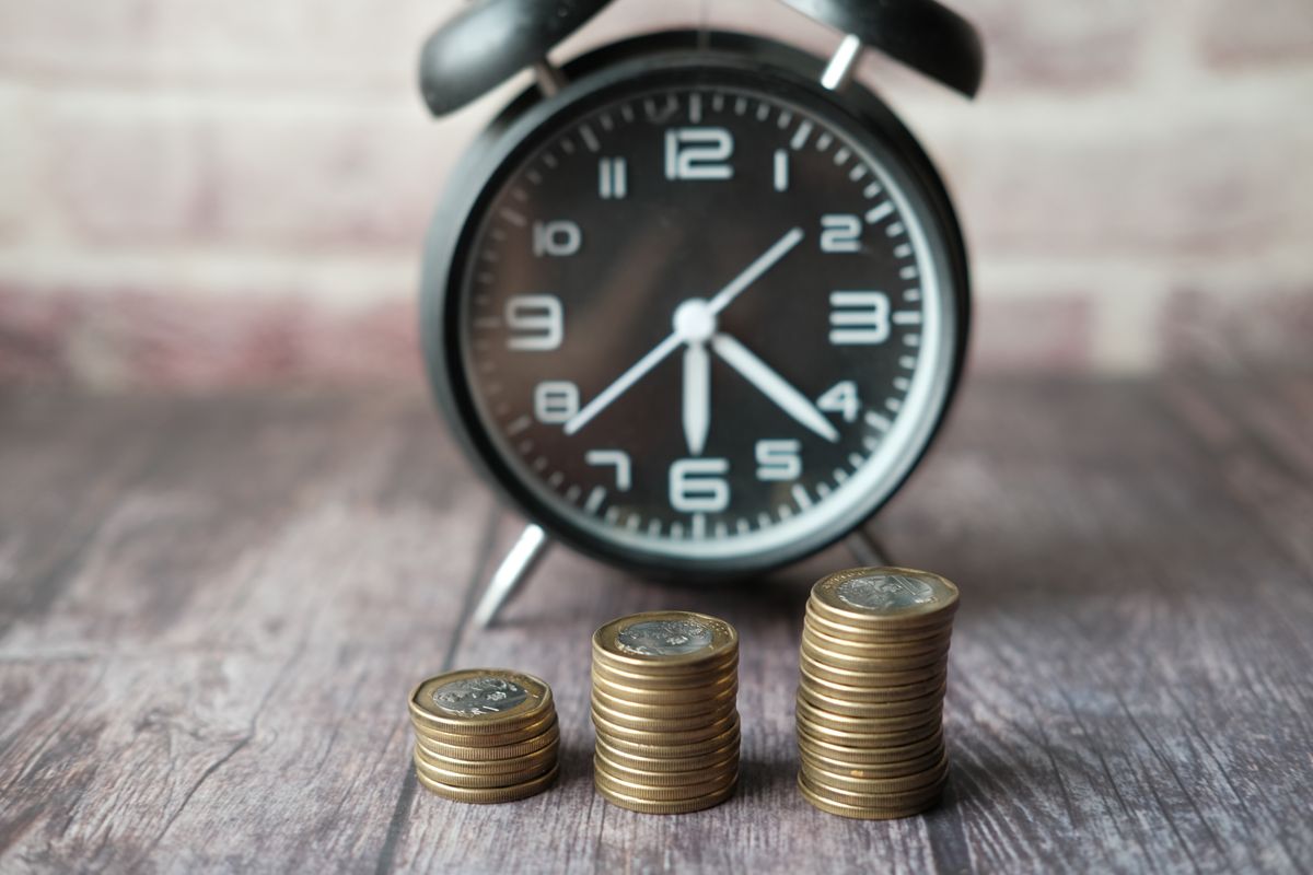 Münzstapel und Uhr als Symbol für Zeit und Geld bei der Altersvorsorge